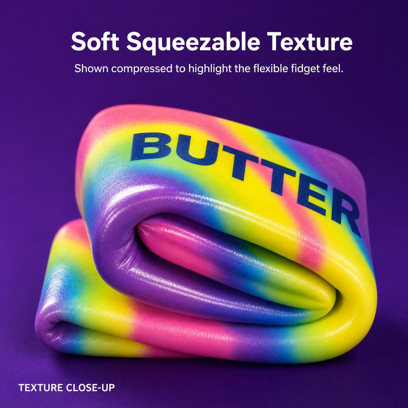 Close-up of the rainbow butter squishy being compressed to show its soft, slow-rebound squeezable texture