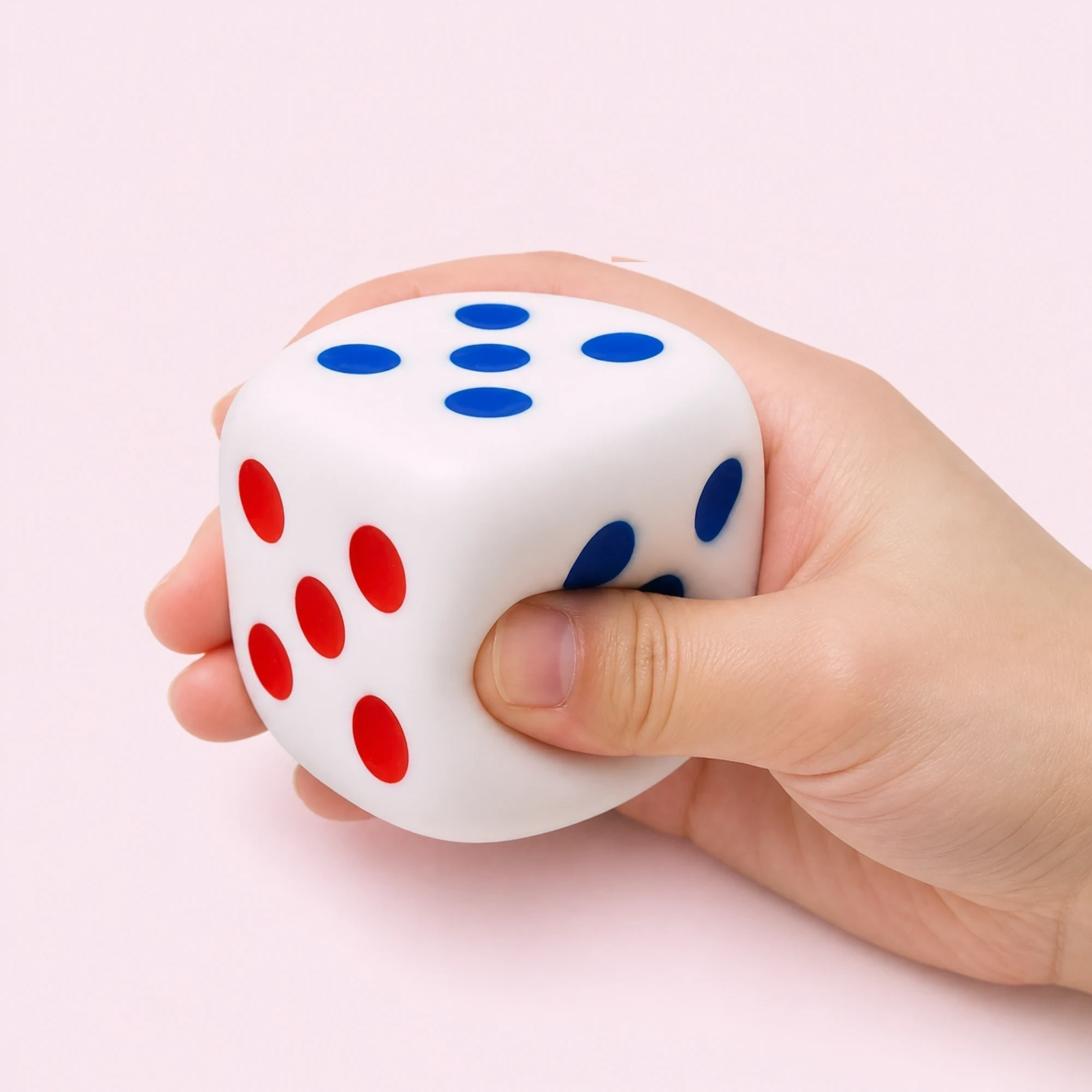 Hand holding a colorful dice-shaped squishy beside a gaming keyboard