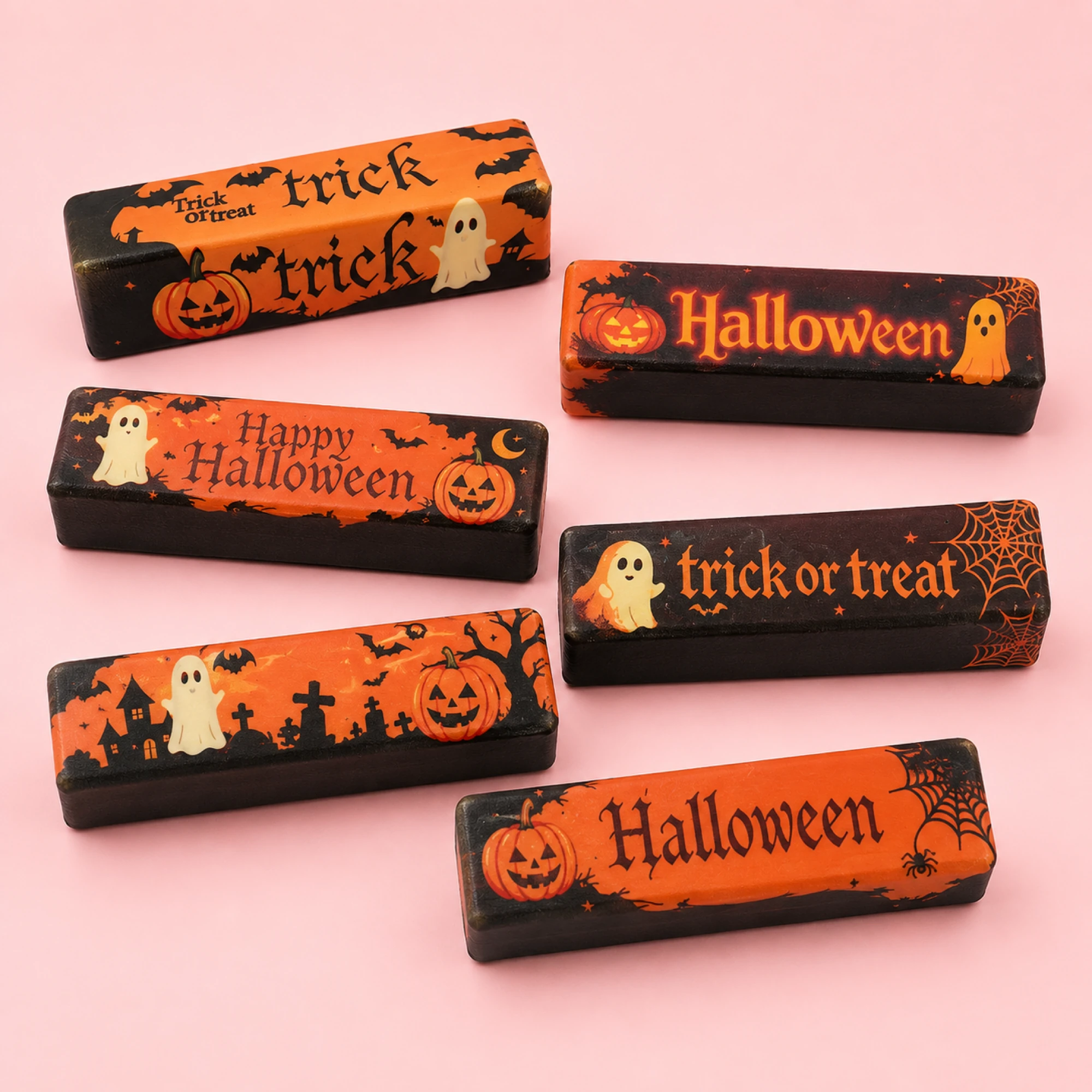 Assorted orange and black Halloween butter squishy designs on a pink background — one random piece per order