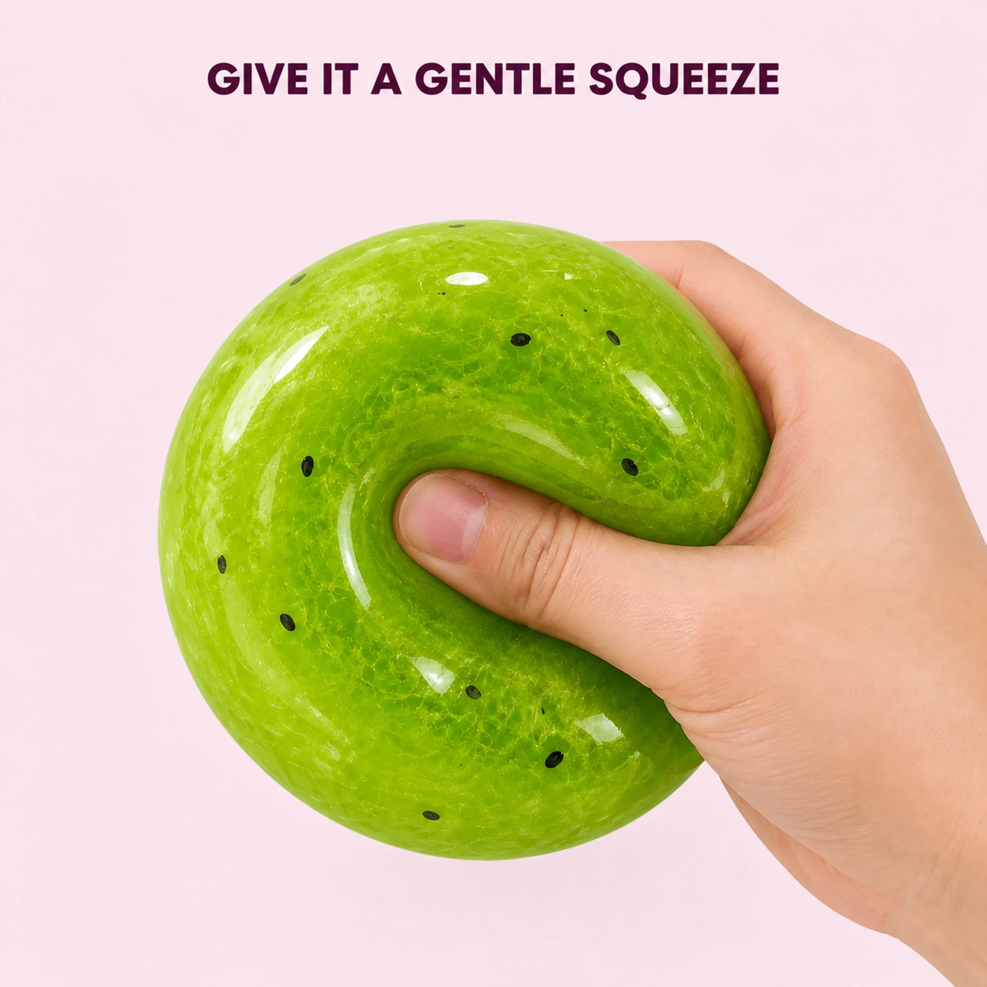 A hand gently squeezing the green kiwi squishy ball