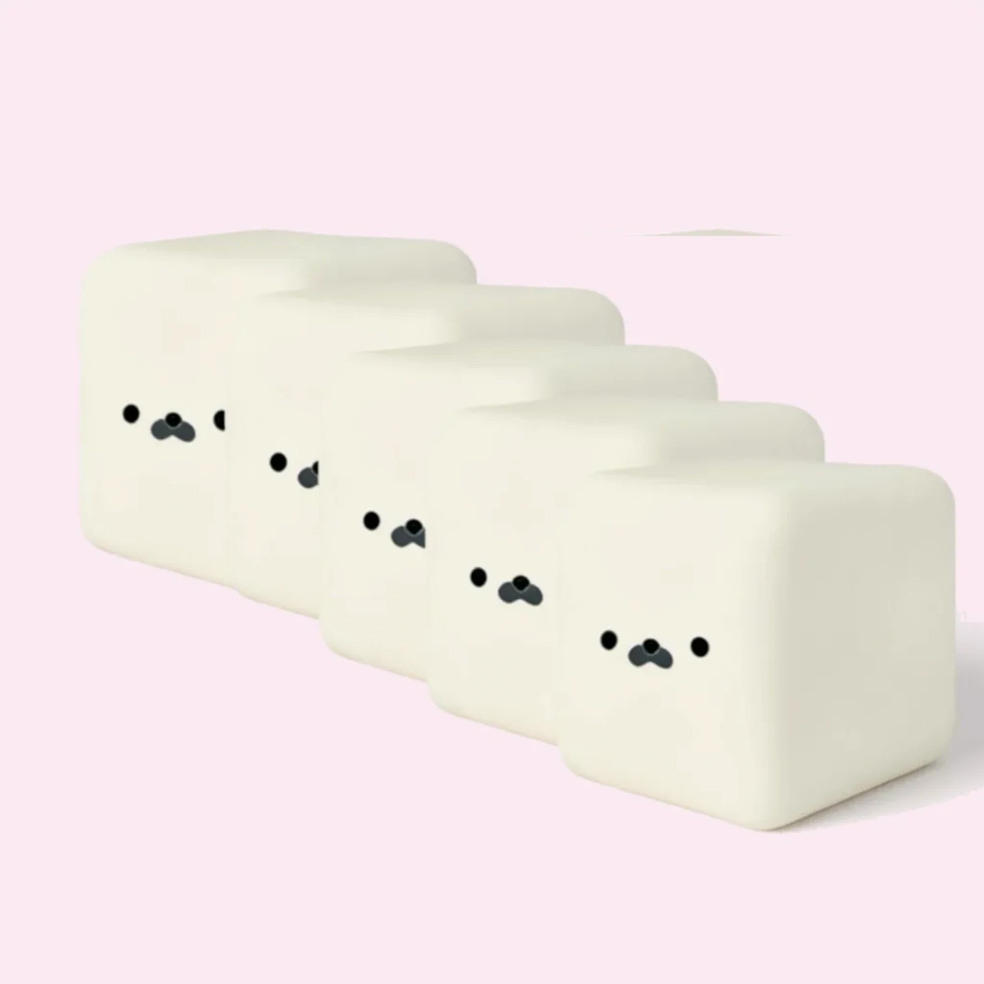 Five cream rounded-square mochi seal squishies on pale pink background